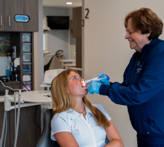 Female dentist examining patient's mouth with intraoral camera